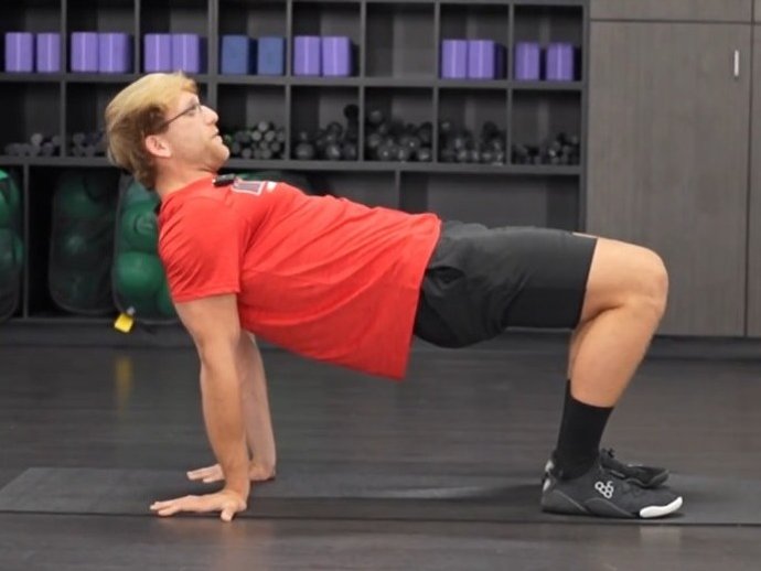 Athlete holding a reverse tabletop position on a gym mat