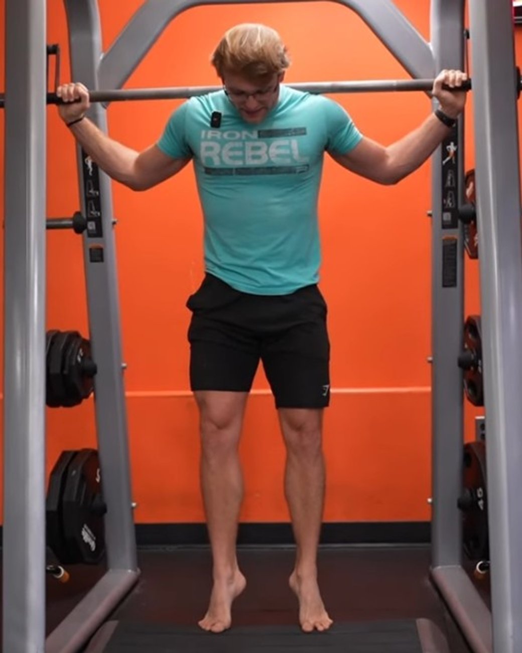 Athlete standing in a squat rack, holding a barbell across the shoulders